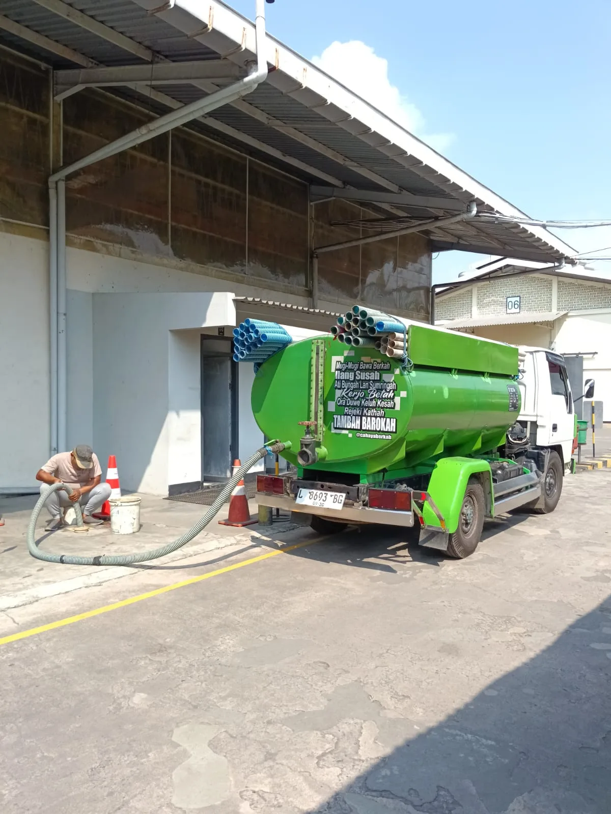 Petugas bekerja menggunakan selang di samping truk tangki sedot WC.